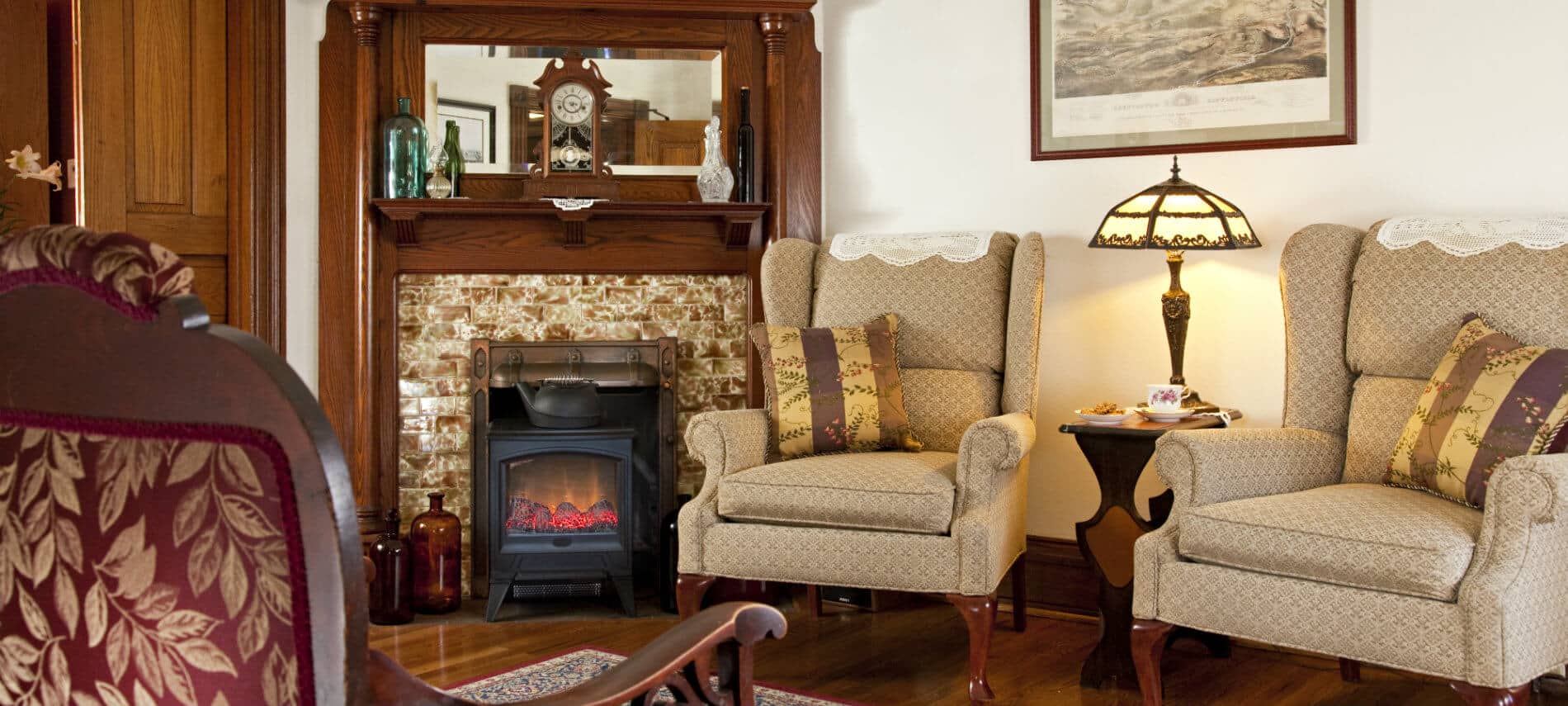 Beautiful room featuring an old fireplace with fire stove in front and two upholstered wing back chairs